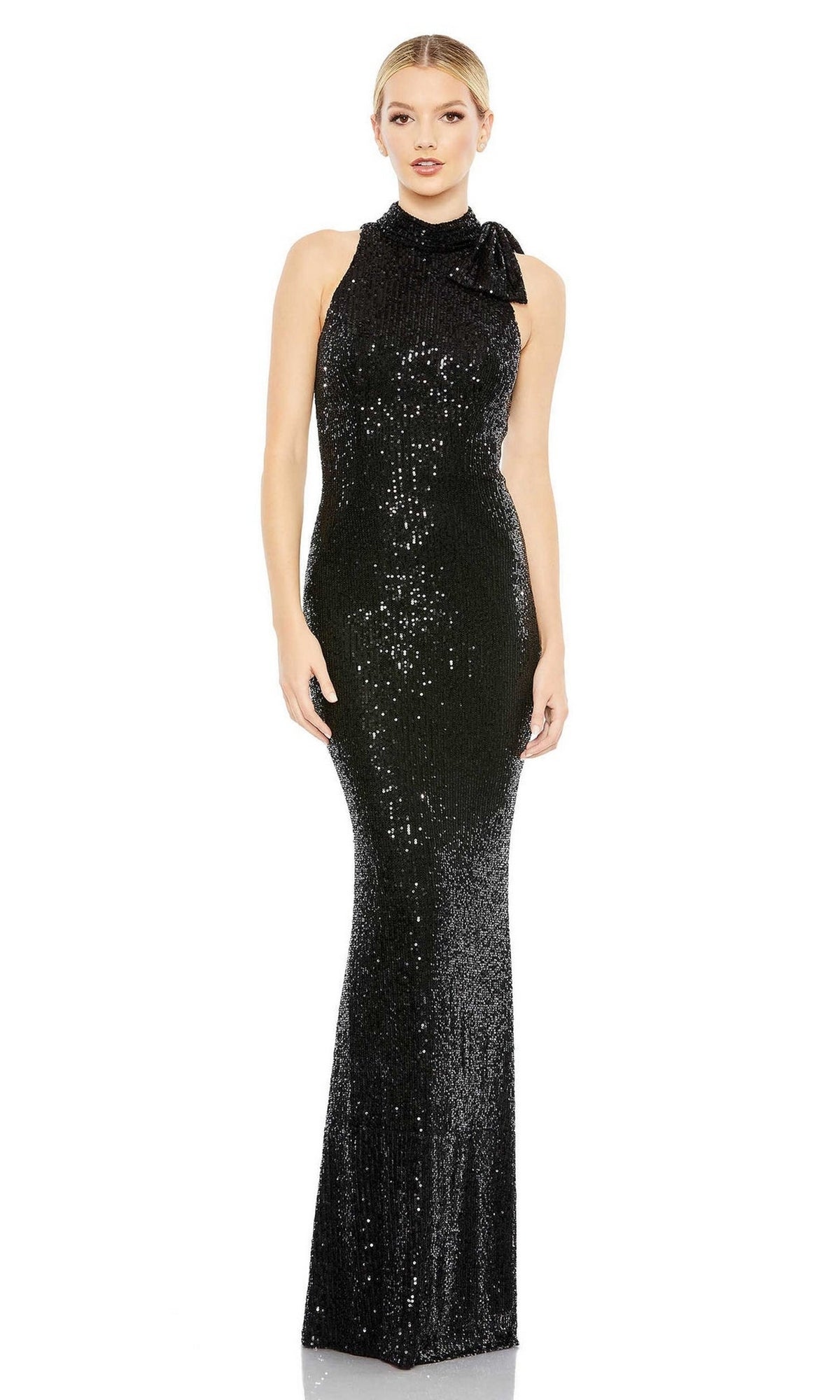 A woman models the Mac Duggal 11280 Bow Long Sequin Formal Dress—a sleeveless, floor-length black gown with shimmering sequins, a high neckline, and a bow detail on one shoulder—standing against a white background.